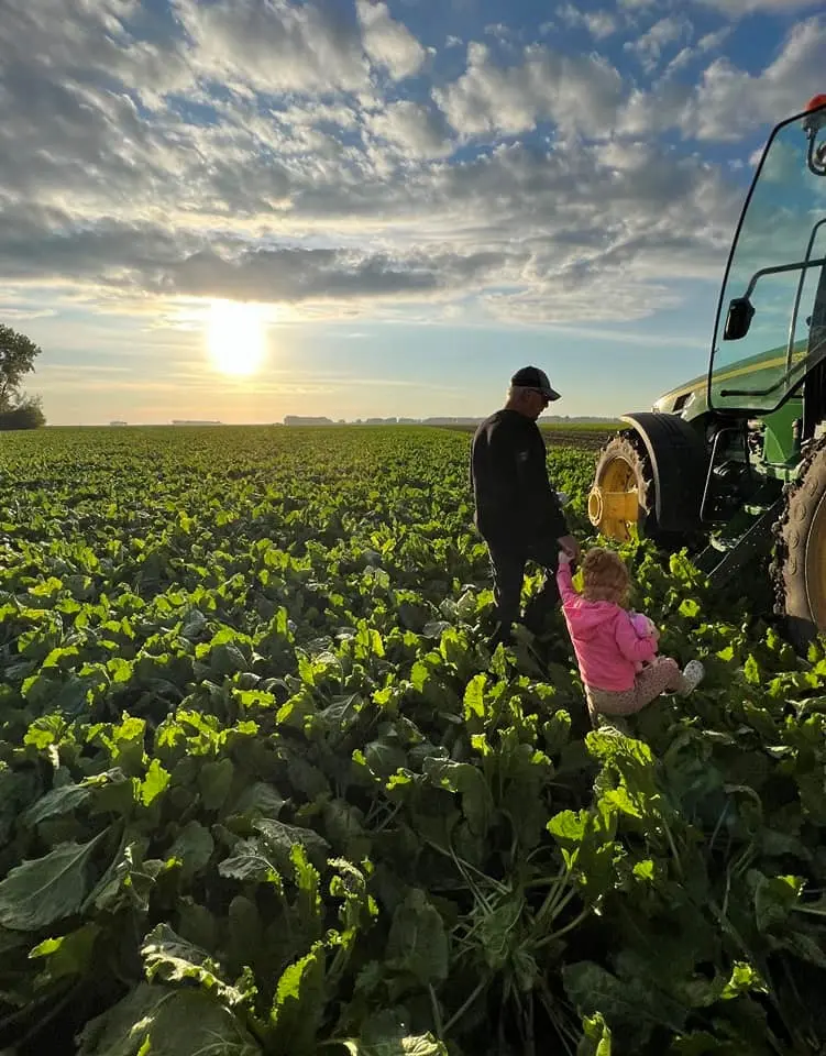 A farmer in a field with his young daughter